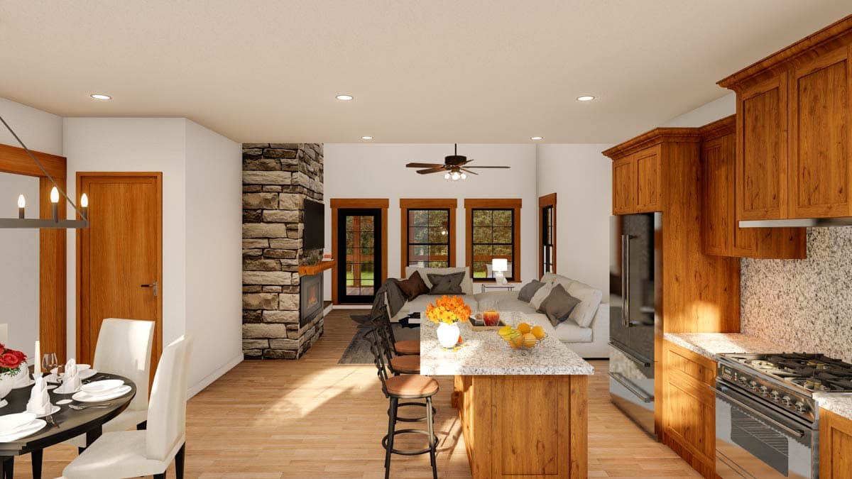 Open concept living space featuring a stone fireplace, kitchen island with seating, dining area, and large windows.
