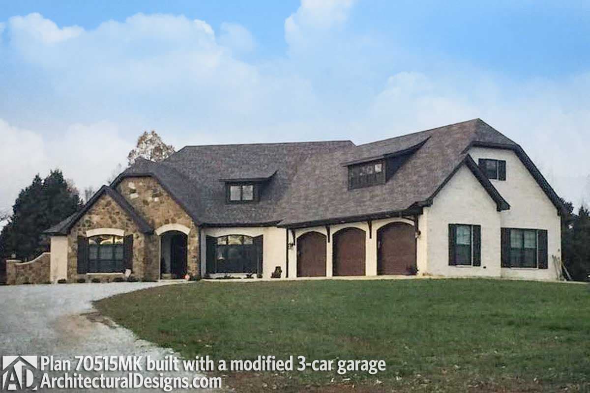 House plan exterior of a one-story home with stone accents, arched doorways, dormers, and a modified three-car garage.