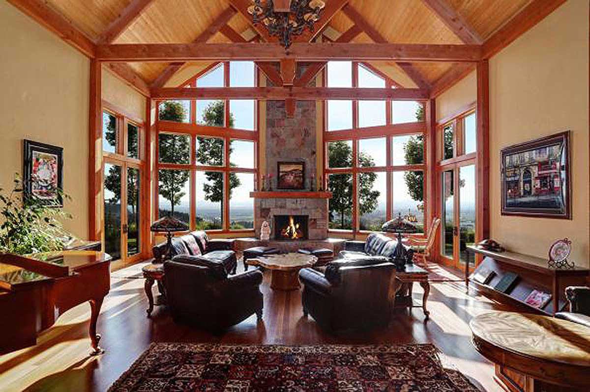Great room with vaulted wood ceiling, stone fireplace, and expansive windows.