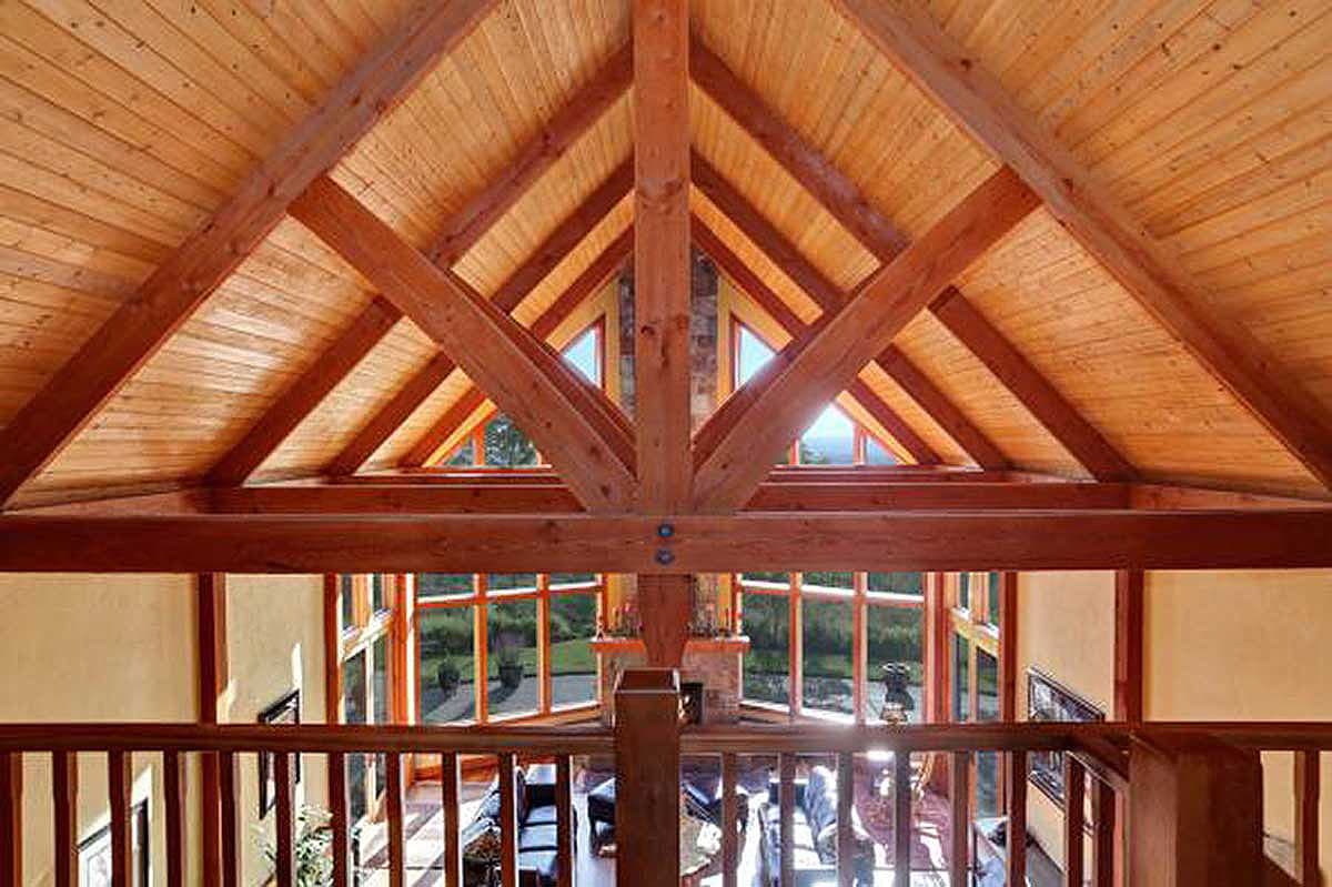 Interior view of a great room with exposed wooden beams and a vaulted, paneled ceiling.