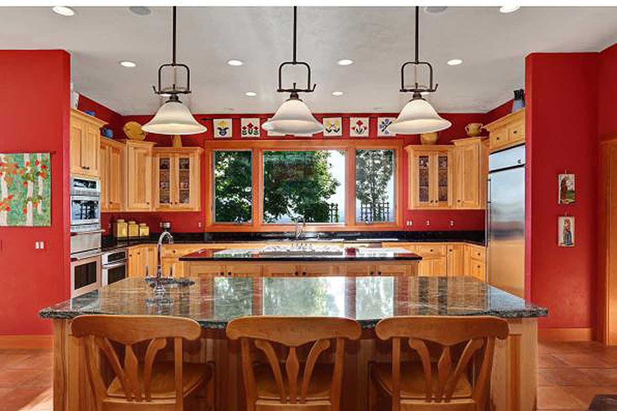 Kitchen with large island, granite countertop, wooden cabinets, stainless steel appliances and a wide window view.