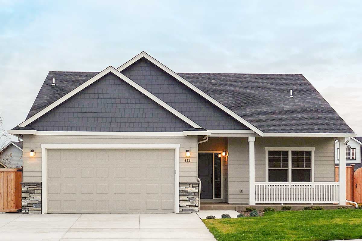 House plan exterior. Ranch style with a gable roof, shake siding, and a covered porch. Features a two-car garage.