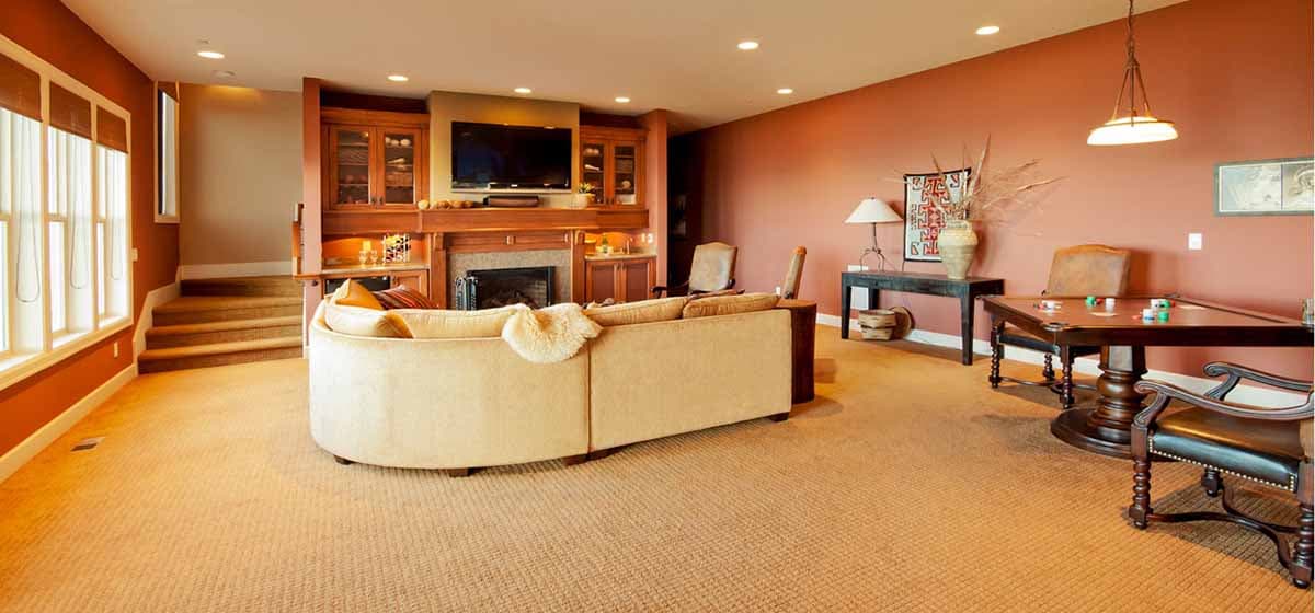 Interior view of a living room with a curved sofa, fireplace, built-in cabinetry, and game table.