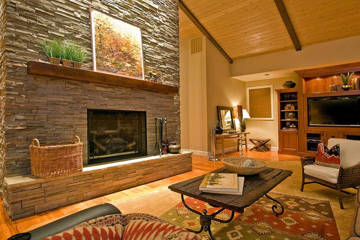 Great room with stacked stone fireplace, vaulted wood-paneled ceiling, and built-in entertainment center.