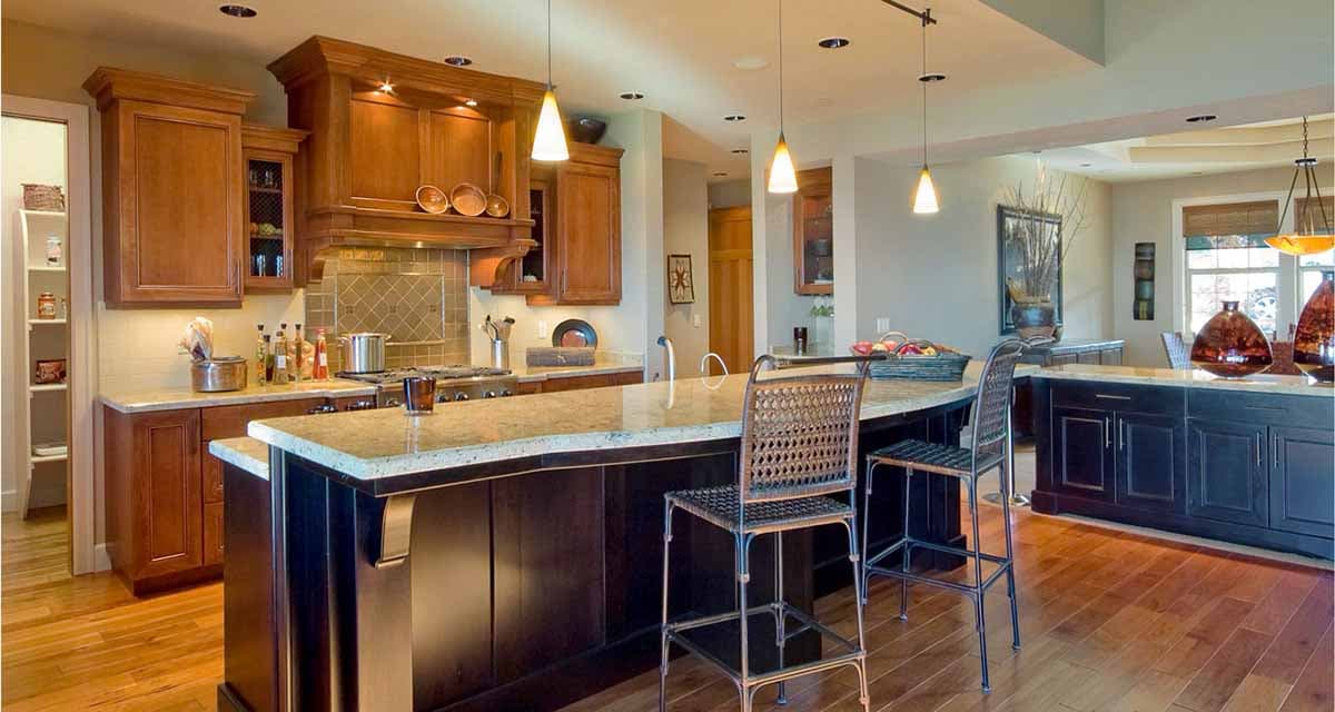 Kitchen with wood cabinetry, granite countertops, a large island with seating, and pendant lighting.