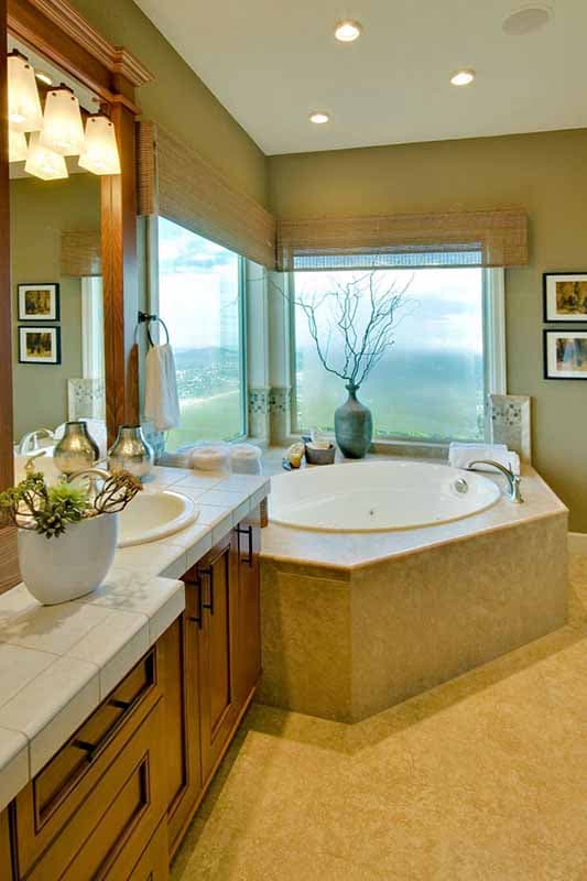 Bathroom with corner jacuzzi tub, double vanity with undermount sinks, and large windows overlooking a scenic view.