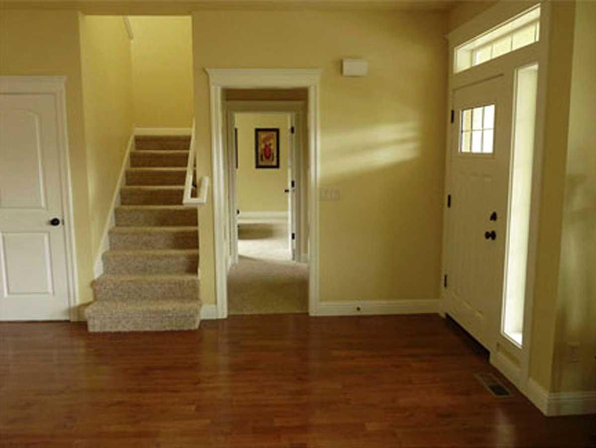 Interior view of a house foyer with a carpeted staircase, a white door, and a white front door with a transom window.