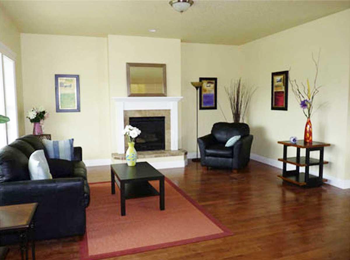 Living room with fireplace, dark leather sofa and armchair, coffee table, and wooden floors.