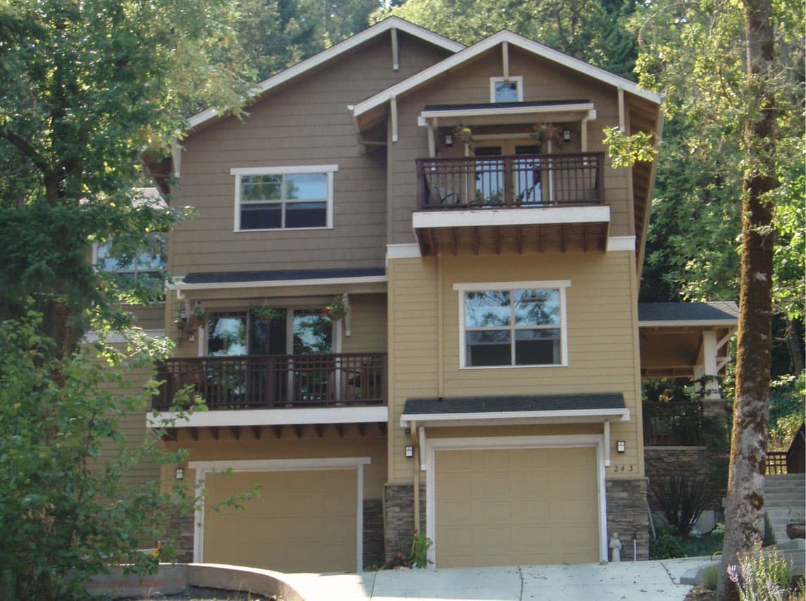 House plan exterior, two stories, with two garages, two balconies, and varied rooflines.