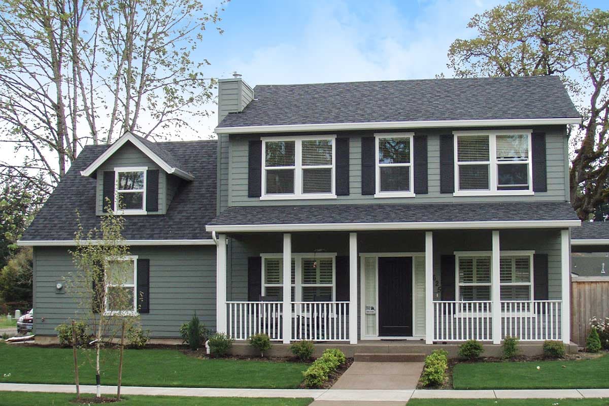 House plan exterior. Two-story home with a front porch, gabled roof, and dormer. Features include black shutters and a chimney.