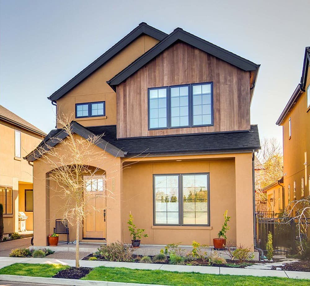 House plan exterior. Two-story with stucco and wood siding. Features include a front porch, gabled roof, and multiple windows.