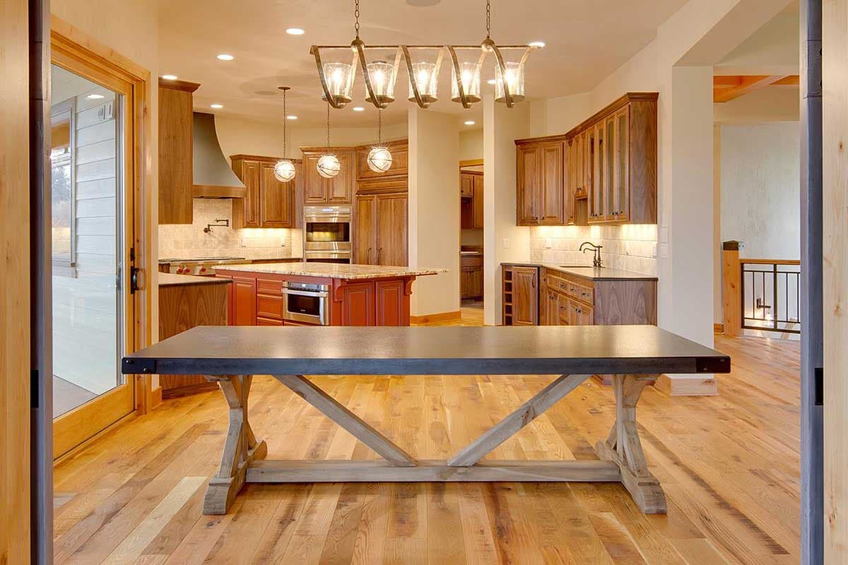 Interior view of an open-concept kitchen with a large island, wood cabinetry, and pendant lighting.