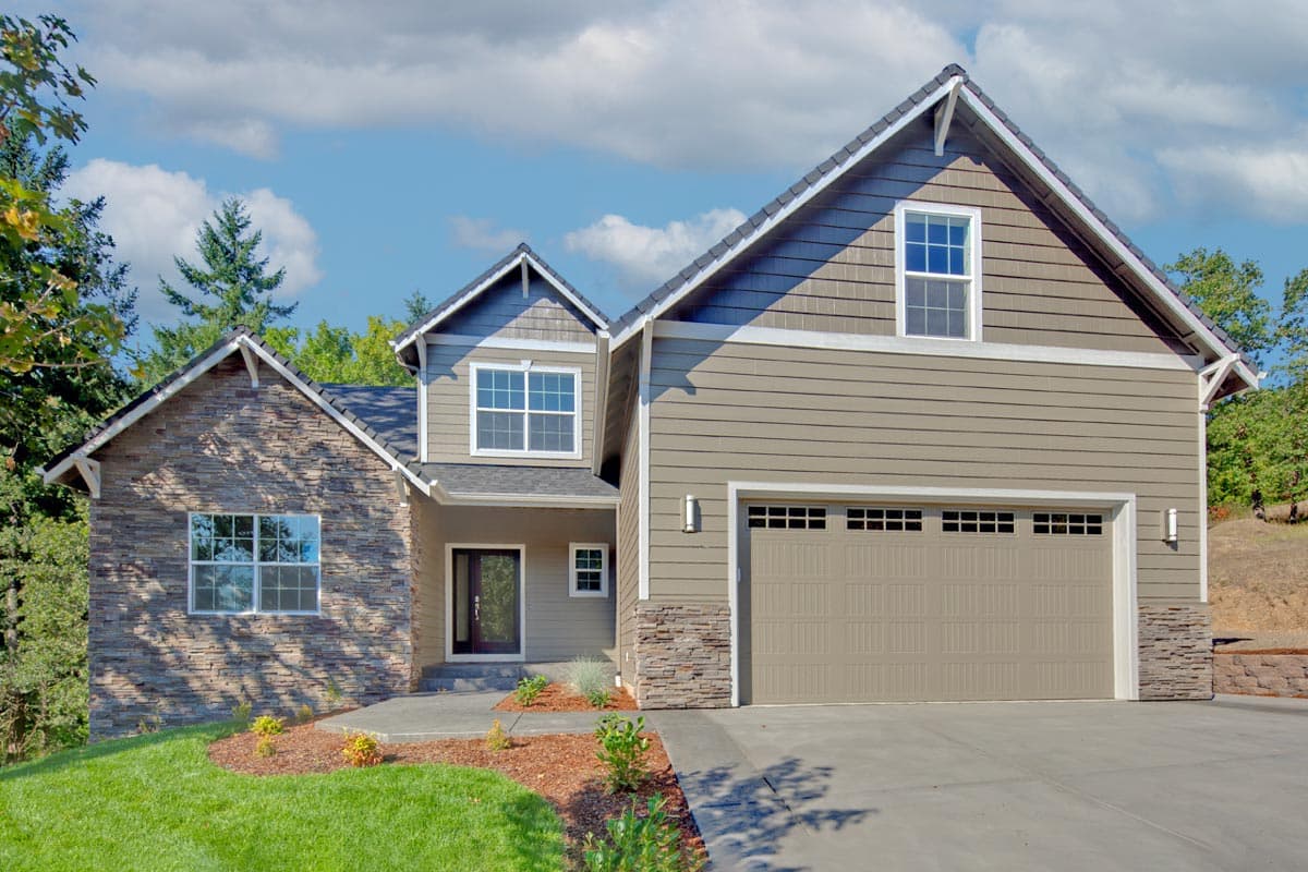 House plan exterior with stone accents, two-story gabled roof, and attached two-car garage. Features a covered entry and multiple windows.