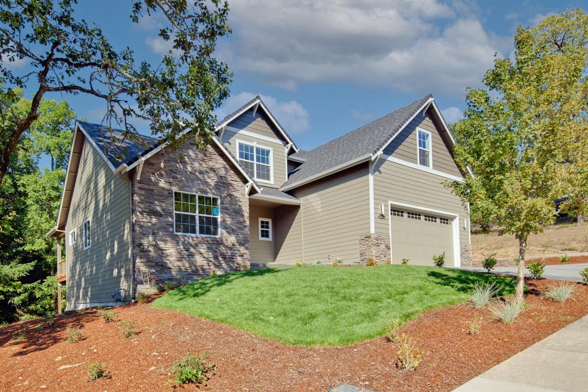 Exterior view of a two-story house plan with stone and vinyl siding, a prominent gable, and a two-car garage.