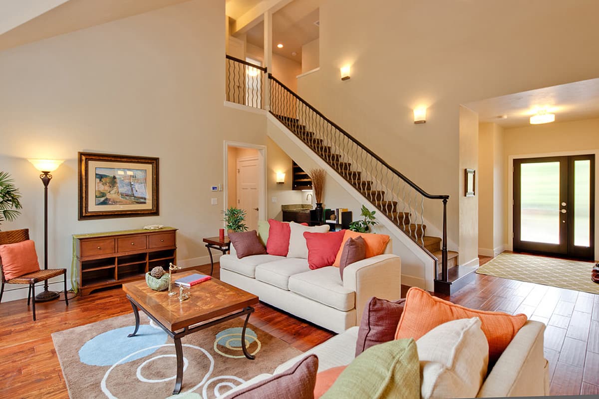 Interior view of a living room with a staircase, double entry doors, and a wet bar area.