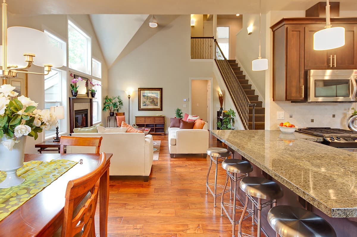 Open concept living area with vaulted ceiling, fireplace, kitchen island with bar seating, and staircase.