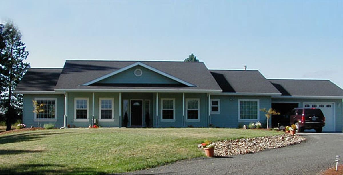 One-story house plan exterior with a central gable, covered front porch, large windows, and attached three-car garage.
