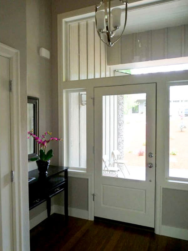 Entryway with glass-paneled door, sidelights, transom window, console table, and overhead light fixture.