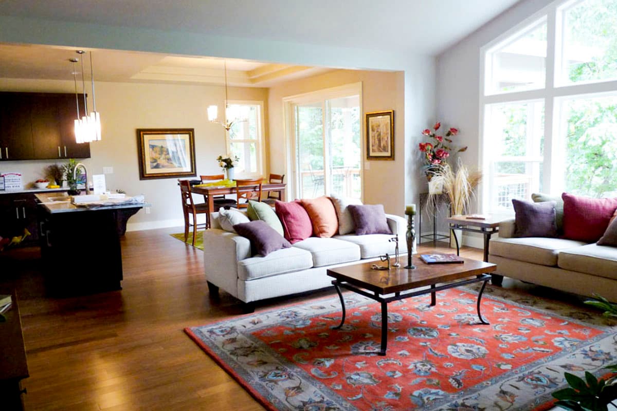 Interior: Open-concept living room with kitchen island, dining area, sofas, fireplace, and vaulted ceiling with large windows.