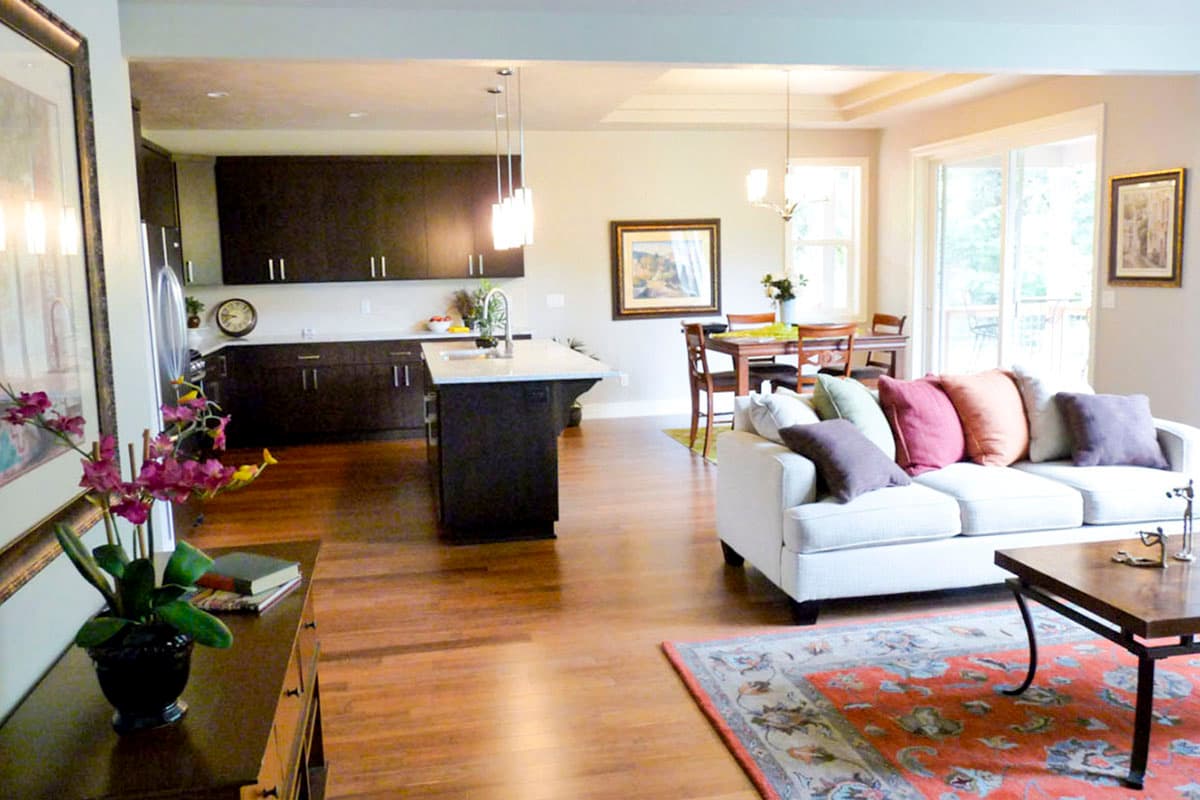 Open concept living space with kitchen island, dining area, and living room featuring a white sofa and fireplace.