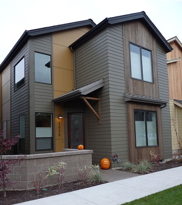 Two-story house plan exterior with a contemporary style, contrasting siding, gabled roof, and an asymmetrical entry overhang.