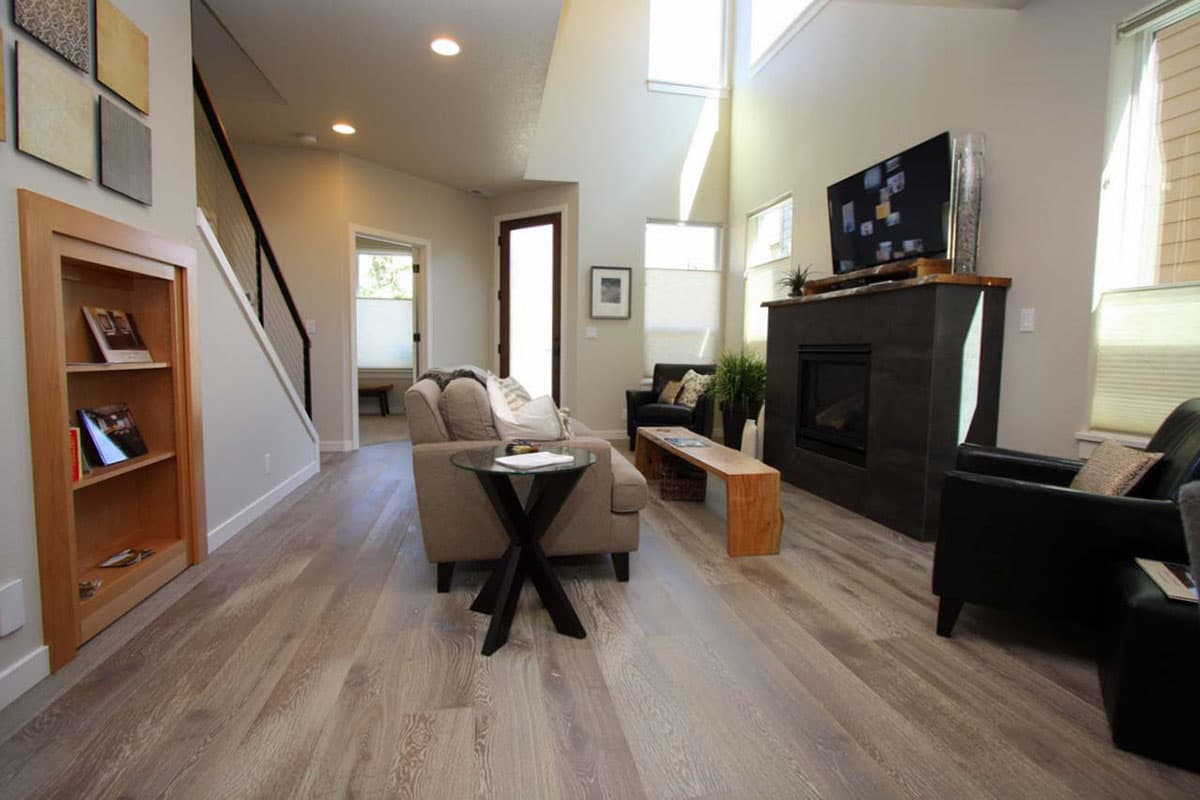 Living room with vaulted ceiling, fireplace, built-in shelving, and natural light from large windows.