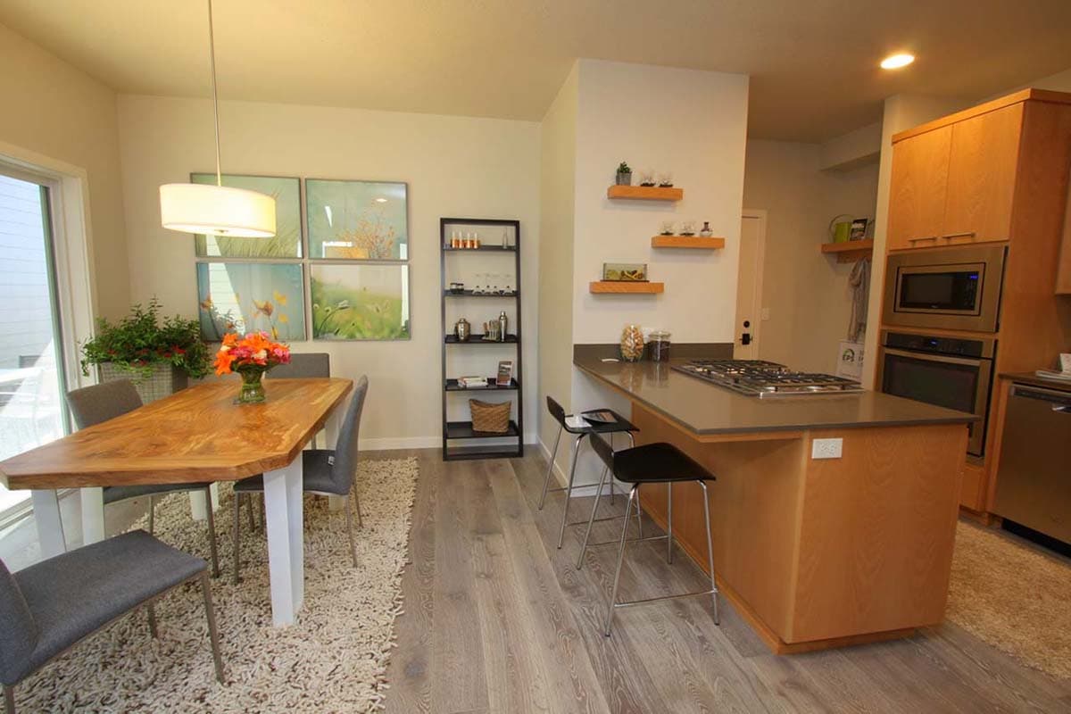 Kitchen and dining area with island cooktop, wooden table, pendant light, and artwork on wall.