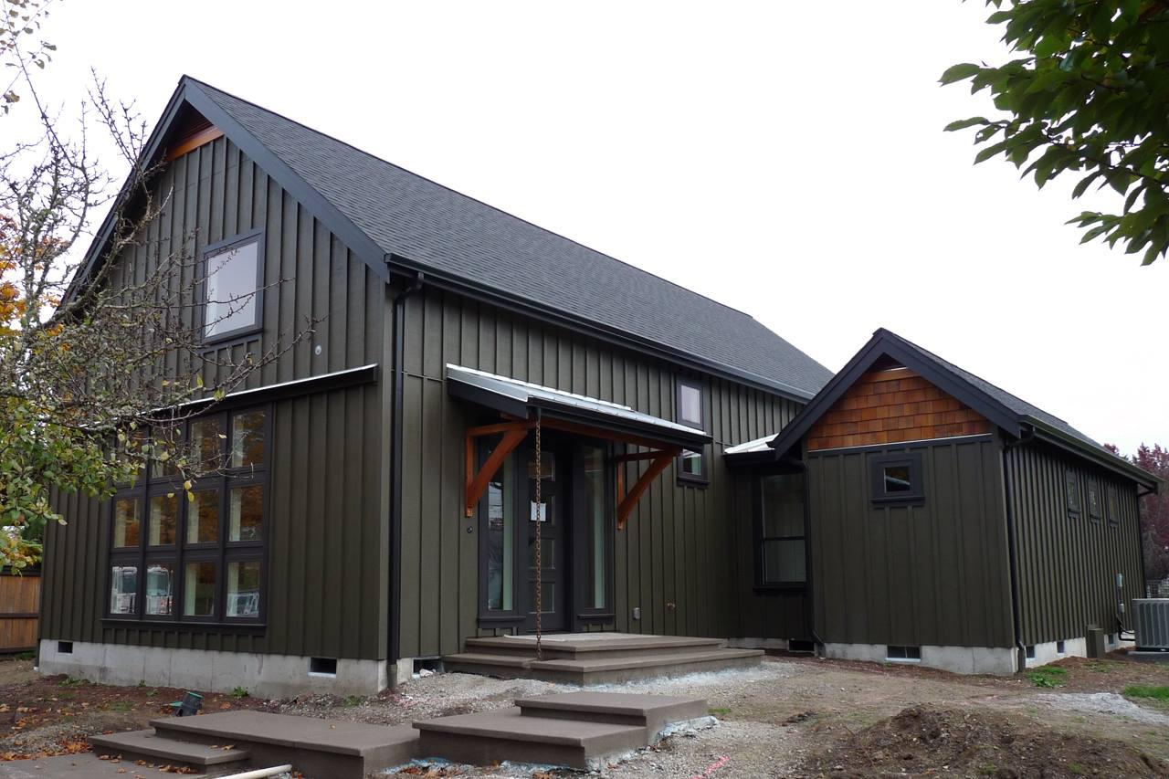 Modern house plan exterior with vertical siding, gable rooflines, and wood-supported entry canopy.