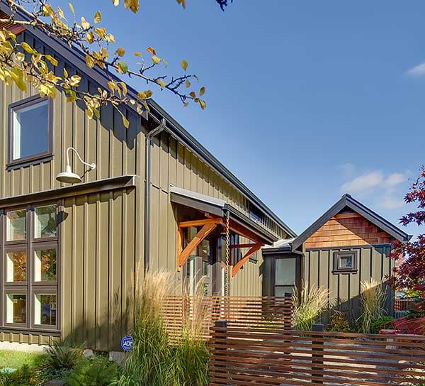 House plan exterior featuring vertical siding, a prominent gable with cedar shingles, and a covered entryway with exposed beams.