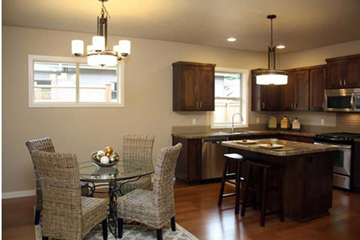 Kitchen and dining area with dark wood cabinets, granite island with seating, and glass-top dining table.