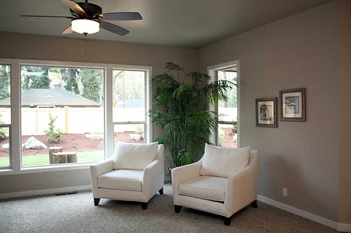 Living area with two armchairs, a large window with views of landscaping, and a ceiling fan.
