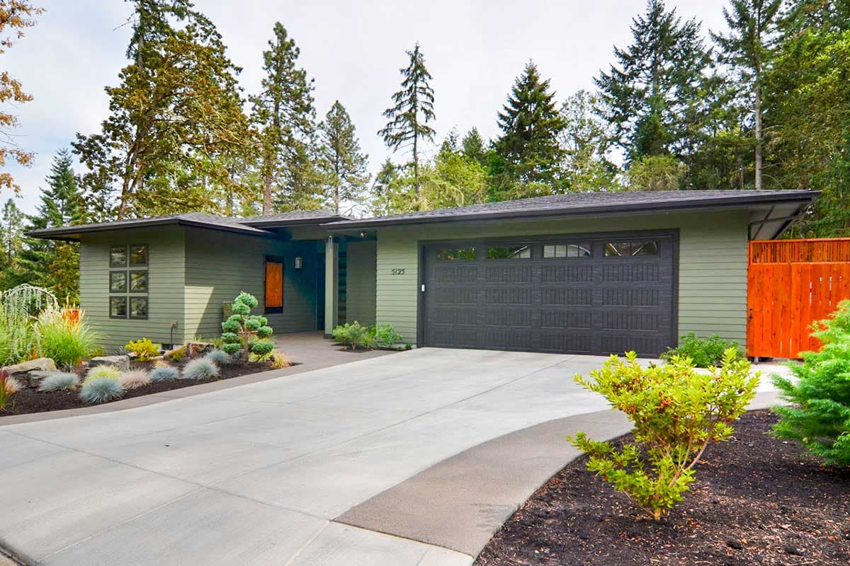 Modern Ranch house plan exterior with a low-pitched roof, wide eaves, large garage door, and geometric windows.