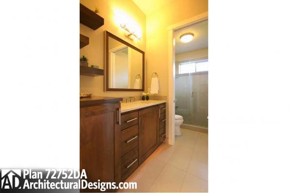 Bathroom with wood vanity, double sink, mirror, and glass-enclosed shower with toilet.