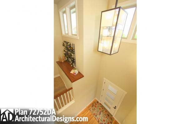 Interior view of entryway with door, stairs, floating shelf with wine rack, and pendant light.
