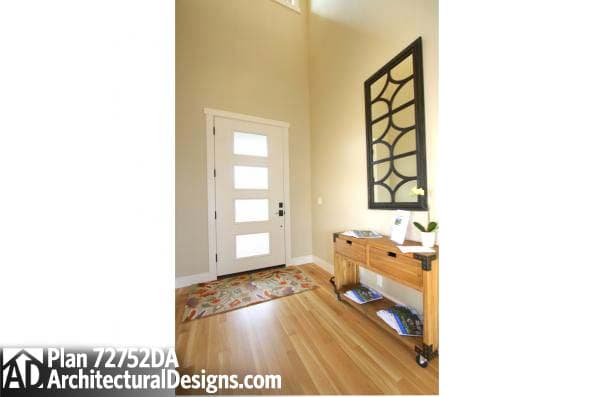 Interior view of an entry with a modern five-panel door, vaulted ceiling, and decorative mirror.