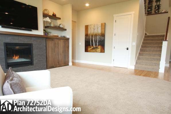 Interior view of a living room with fireplace, television, built-in cabinets, and stairs leading upstairs.