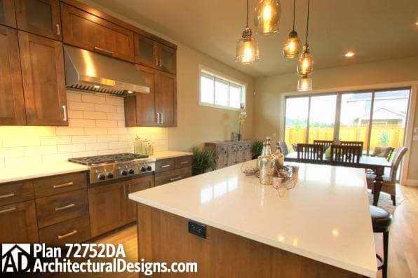 Kitchen with shaker cabinets, gas range, subway tile backsplash, and island with seating. Adjacent dining area with large windows.