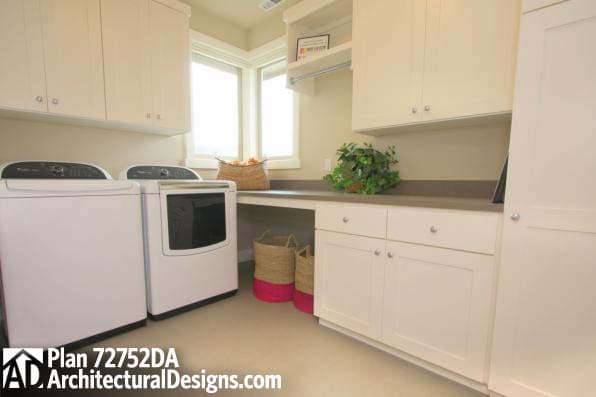Laundry room with white cabinets, washer and dryer, built-in counter, and windows.
