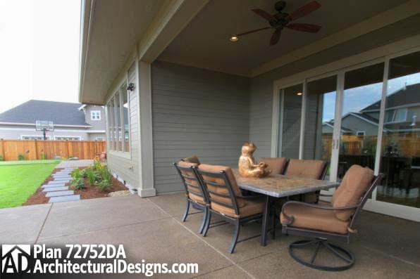 Covered patio with outdoor dining set and sliding glass doors. Exterior house plan 72752DA.