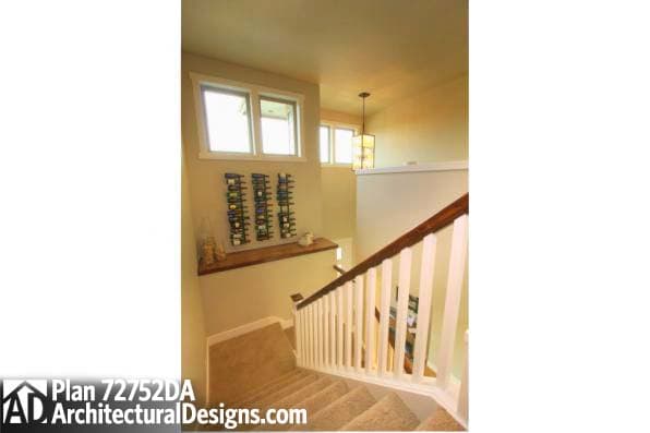 House plan interior view showing a carpeted staircase with white balusters and a wooden handrail. A wall-mounted wine rack is visible.