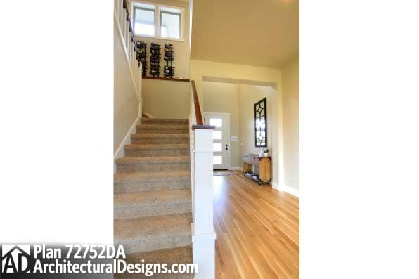 Interior view of house plan with carpeted staircase, wine rack, entryway with glass-paneled door, and hardwood floors.