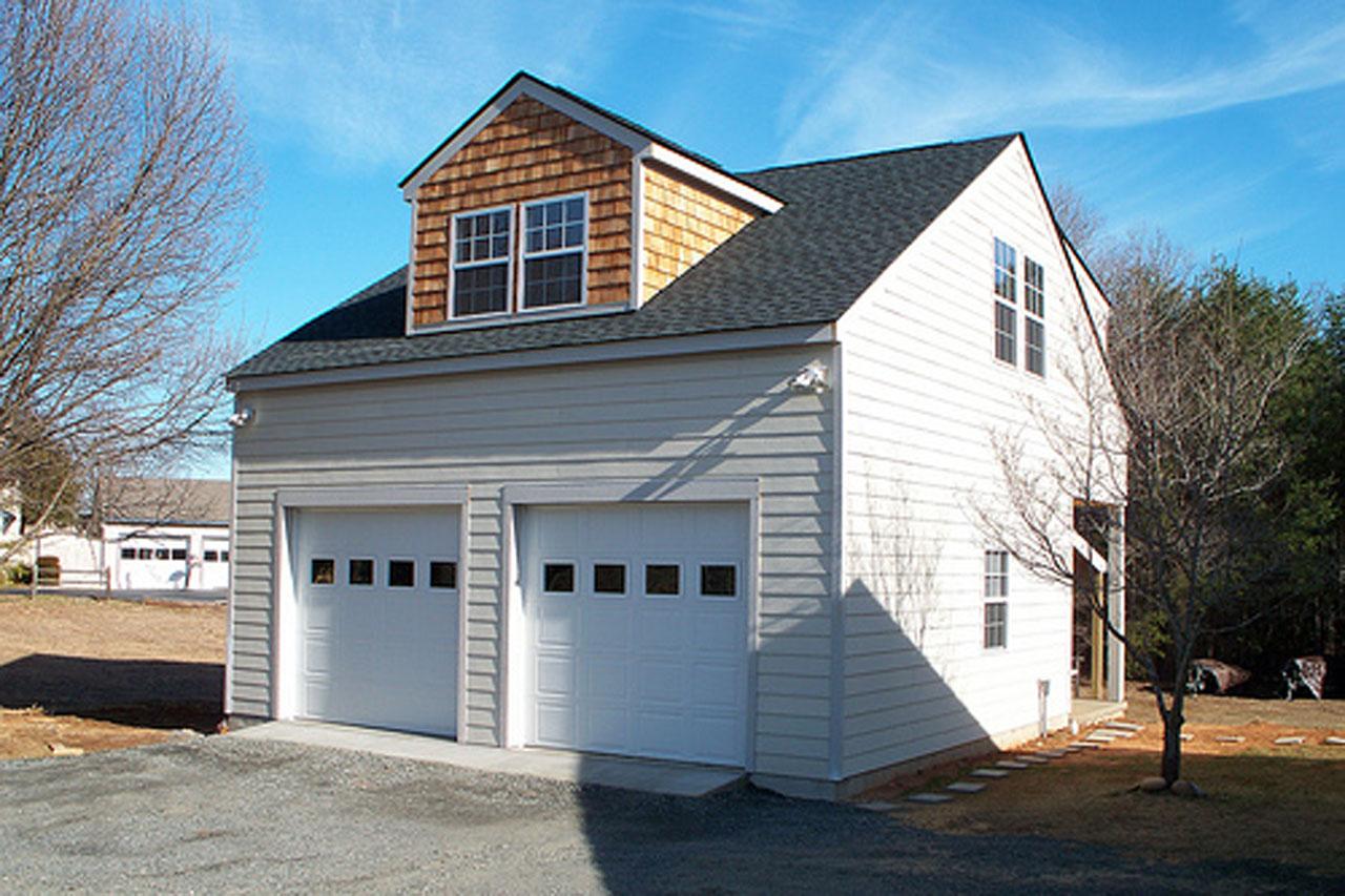 House plan exterior with a two-car garage, sided walls, and a dormer with cedar shingles and double-hung windows.