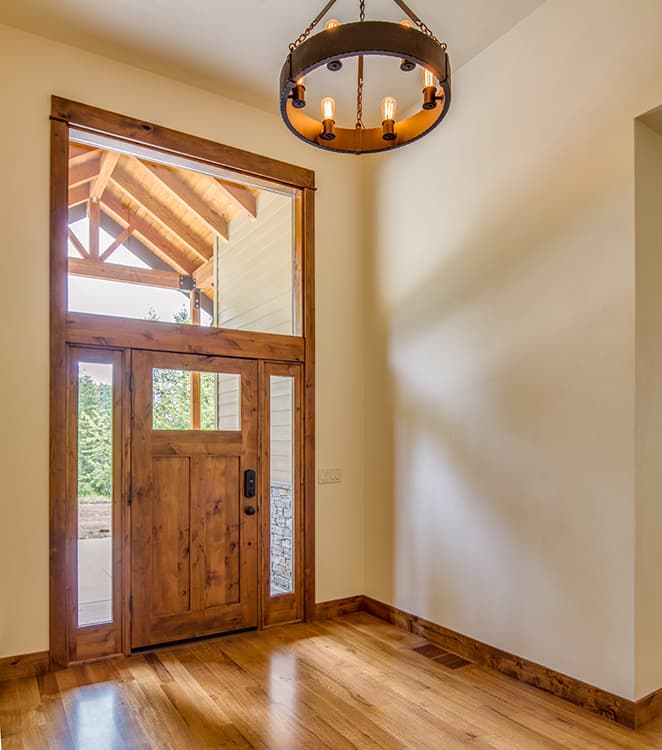 House plan interior: Entryway with wooden double door, sidelights, transom window, and rustic chandelier.