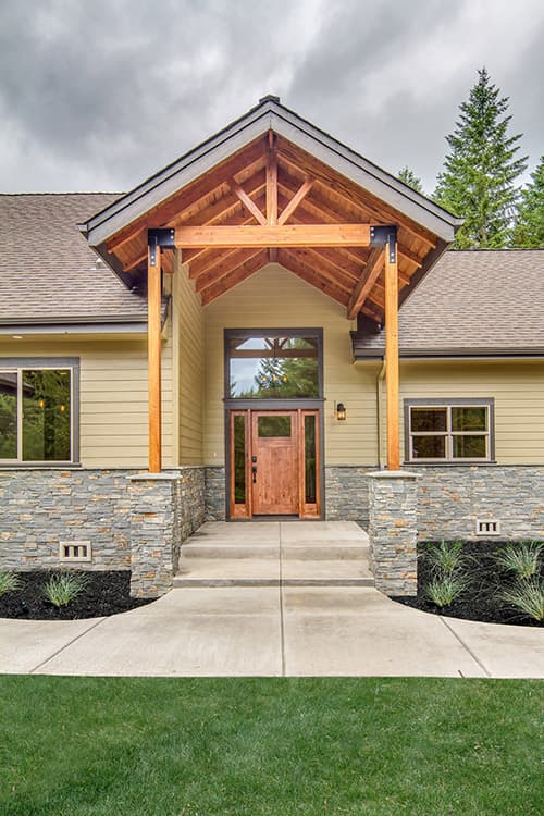 House plan exterior: Single-story modern rustic design with stone accents, wood-clad gable roof entry, and double wooden doors.