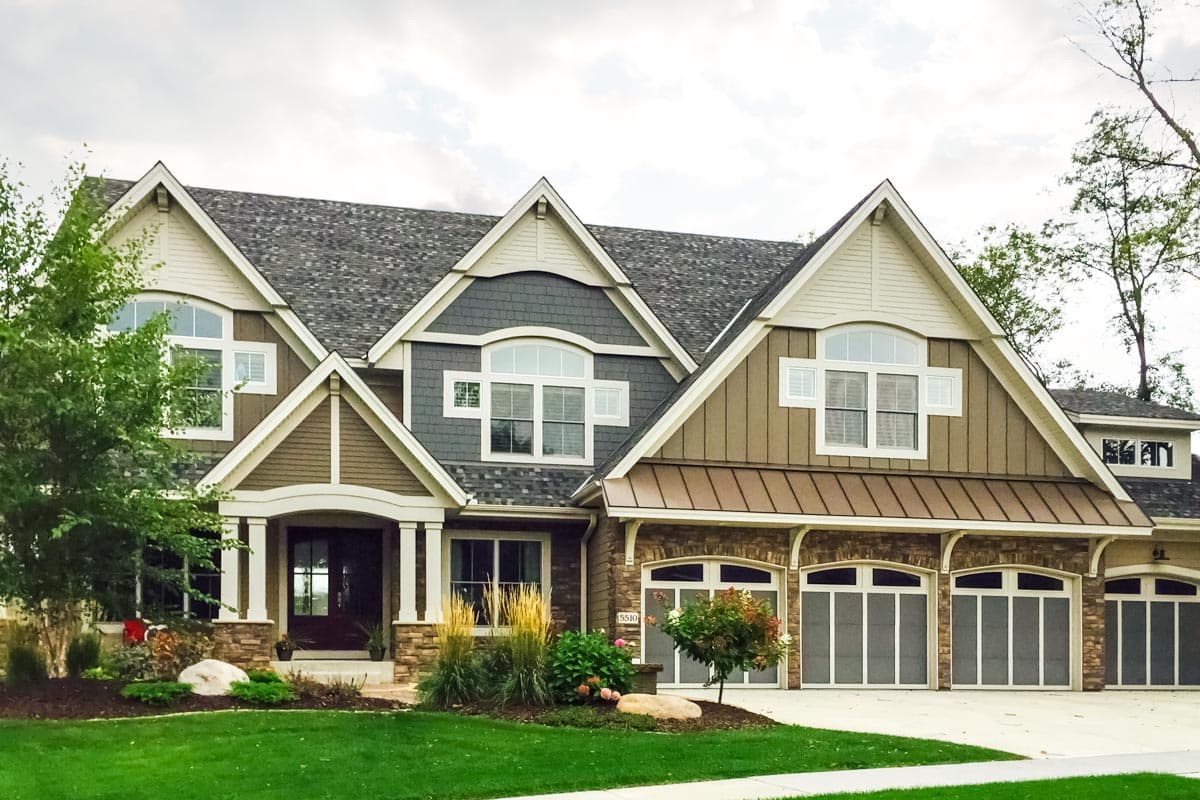 Craftsman house plan exterior with multiple gables, stone accents, covered entryway, and four-car garage.