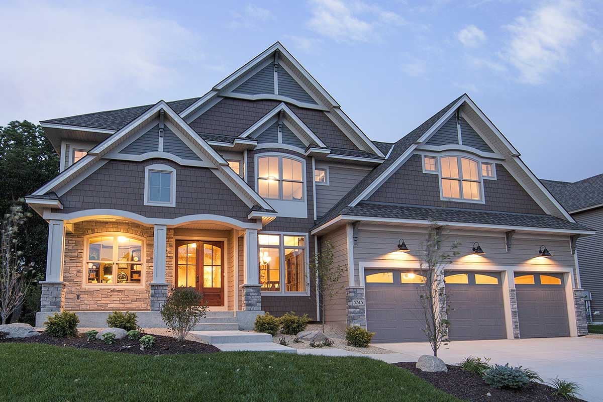 House plan exterior. Two-story home with Craftsman style. Features include gabled rooflines, arched entry porch, and three-car garage.