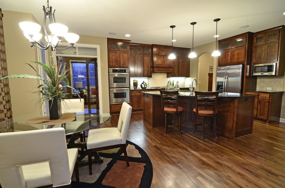 Kitchen featuring dark wood cabinets, double ovens, island with seating, and pendant lighting.