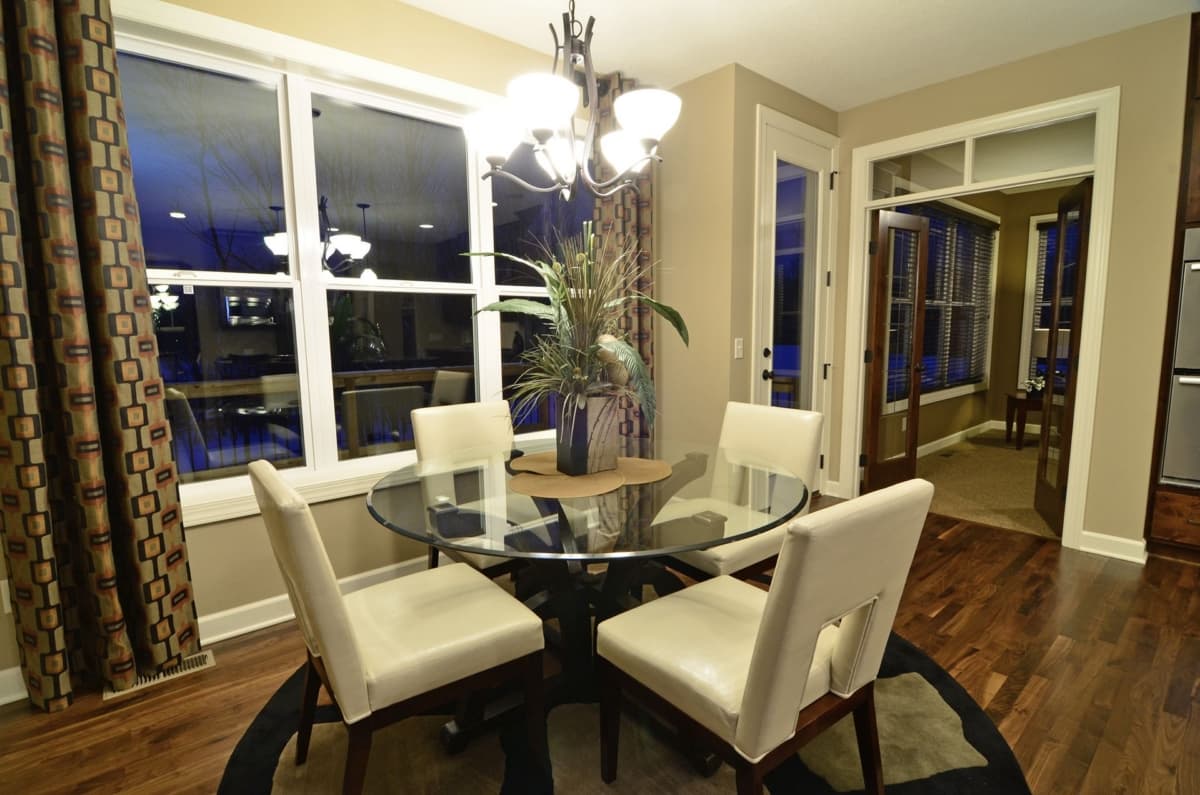 Interior dining area with glass-top table, four chairs, large window, and French doors.