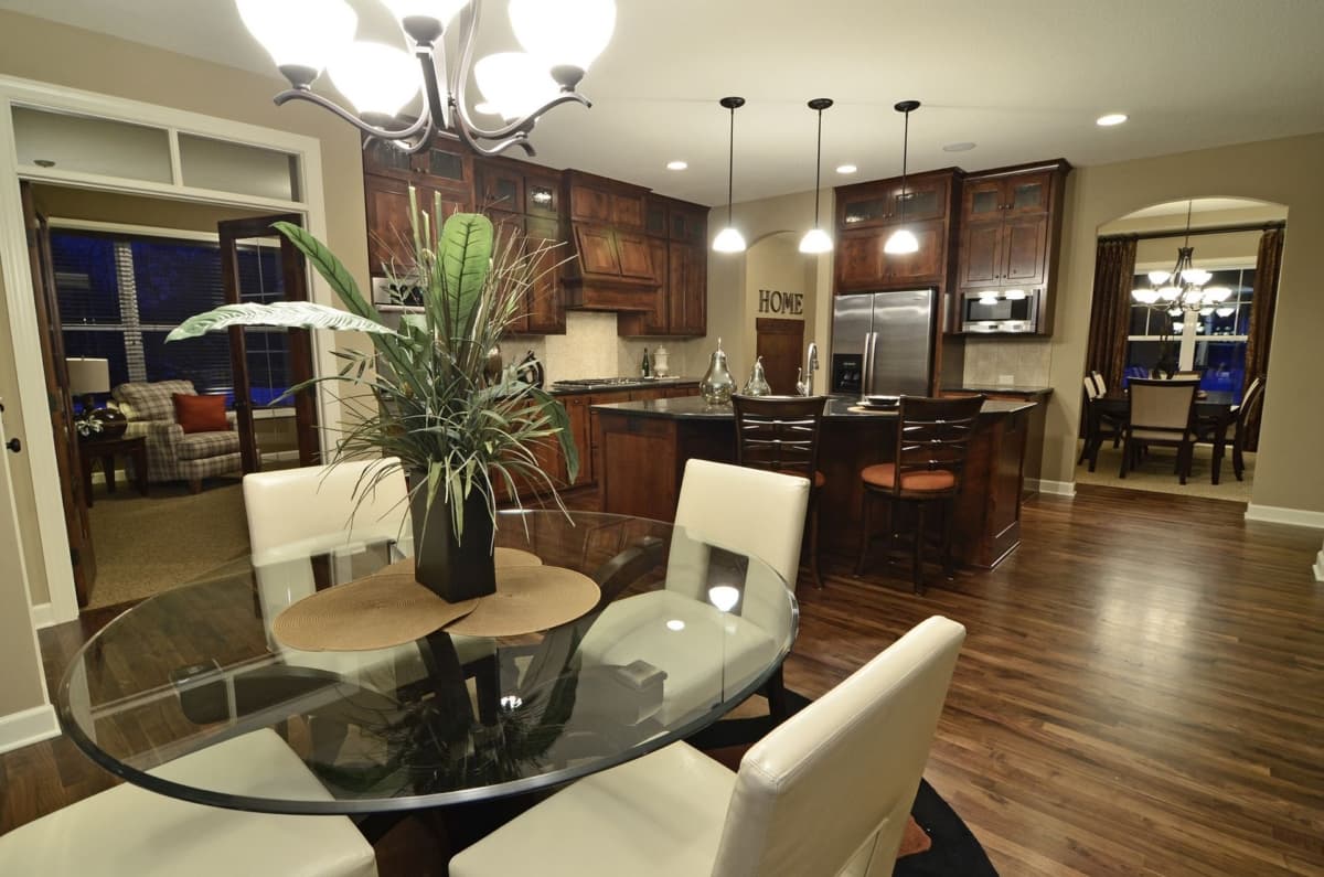 Open-concept kitchen with island and dark wood cabinets, adjacent dining area, and view into living room.