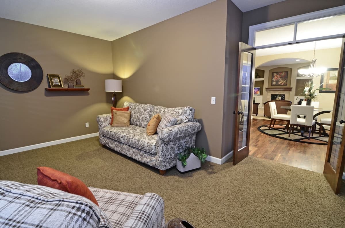 Living room with floral sofa, decorative mirror, and view into dining room with table and chairs.